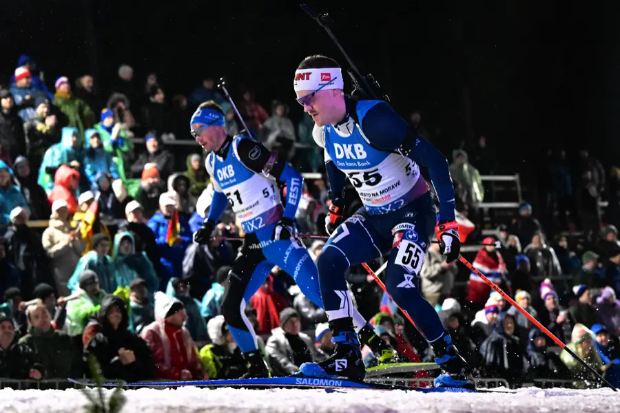 Dvojice biatlonistů v závodě před zaplněnou tribunou v Novém Městě na Moravě